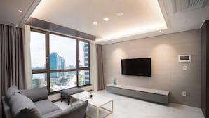 Una sala de estar moderna con sofá, mesa de centro y un televisor de pantalla plana montado en la pared.
