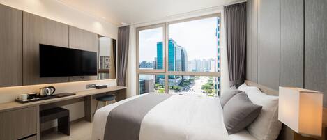 Habitación de hotel moderna con una cama grande, un escritorio, un televisor de pantalla plana y vistas a la ciudad.