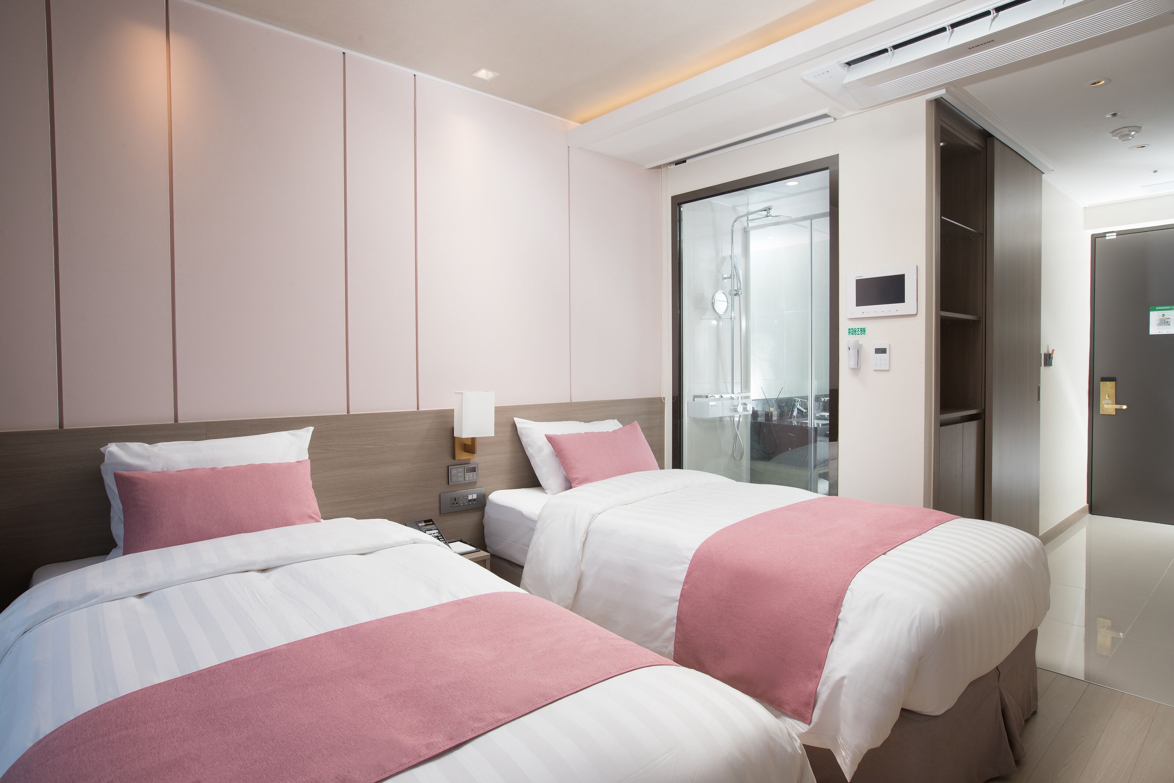 Une chambre d’hôtel avec deux lits, un espace douche et une armoire.