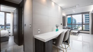 Una habitación de hotel moderna con un ventanal grande, un área de comedor y una cama.