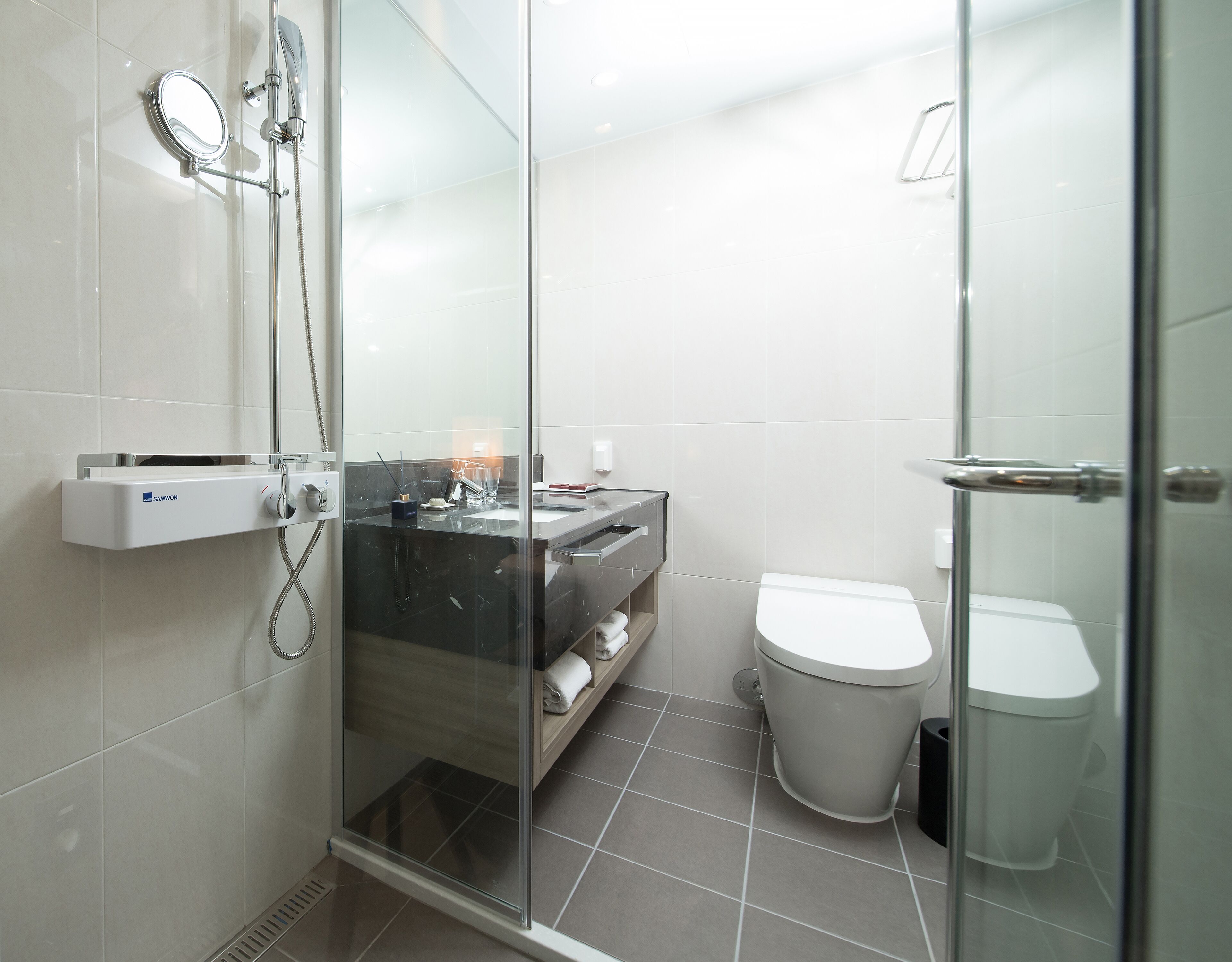 Un baño moderno con ducha envuelta en vidrio, inodoro y tocador con espejo.
