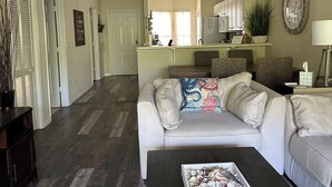 A spacious living room with a grey sofa, a coffee table with decorative items, and a kitchen in the background. - Marco Island Breeze in Naples (Naples)