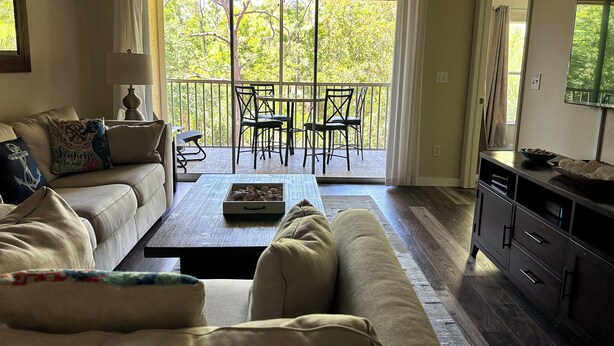 A living room with a sofa, coffee table, and a dining area with chairs and a table. - Marco Island Breeze in Naples (Naples)