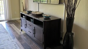 A modern living room with a dark wooden floor, a black console table with decorative bowls, a large mirror, and a tall vase with branches. - Marco Island Breeze in Naples (Naples)