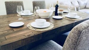 A dining table set with white plates, bowls, and wine glasses, surrounded by grey upholstered chairs. - Marco Island Breeze in Naples (Naples)