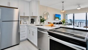 A modern kitchen with stainless steel appliances, white cabinetry, and a large island. - Oceanview Condo w/ Balcony – Steps to Cocoa Beach Pier! (Cocoa Beach)