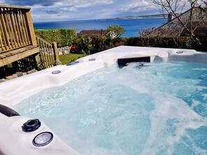 A hot tub with a view of the ocean and a wooden deck. - St Ives & Carbis Bay beach sea views with Hot Tub  & EV charger  (Carbis Bay)