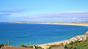 A coastal view with a beach, houses, and a clear sky.