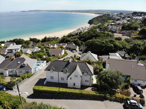 A coastal residential area with houses, a beach, and a clear view of the sea. - St Ives & Carbis Bay beach sea views with Hot Tub  & EV charger  (Carbis Bay)