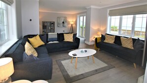 A modern living room with two dark sofas, a round coffee table, and a bookshelf.