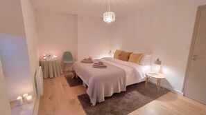 A bedroom with a bed, bedside table, chair, and a hanging light fixture. - Family home between the countryside and the sea, 800 m from the beach (Trégunc)
