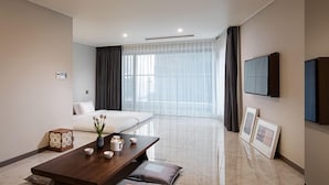 A modern hotel room with a bed, a dining table with tea set, a TV, and a large window with curtains. - Busan Yeongmu Parade Hotel Haeundae Beach (Busan)