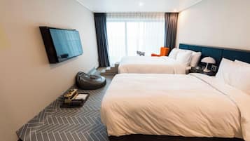 Habitación de hotel con dos camas, televisión, escritorio con lámpara y ventana con cortinas.