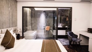 Una habitación de hotel moderna con una cama grande, un baño con bañera, ducha y un escritorio con silla.