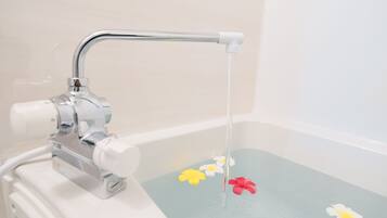 A bathtub with a faucet and water flowing into it, surrounded by floating flowers.