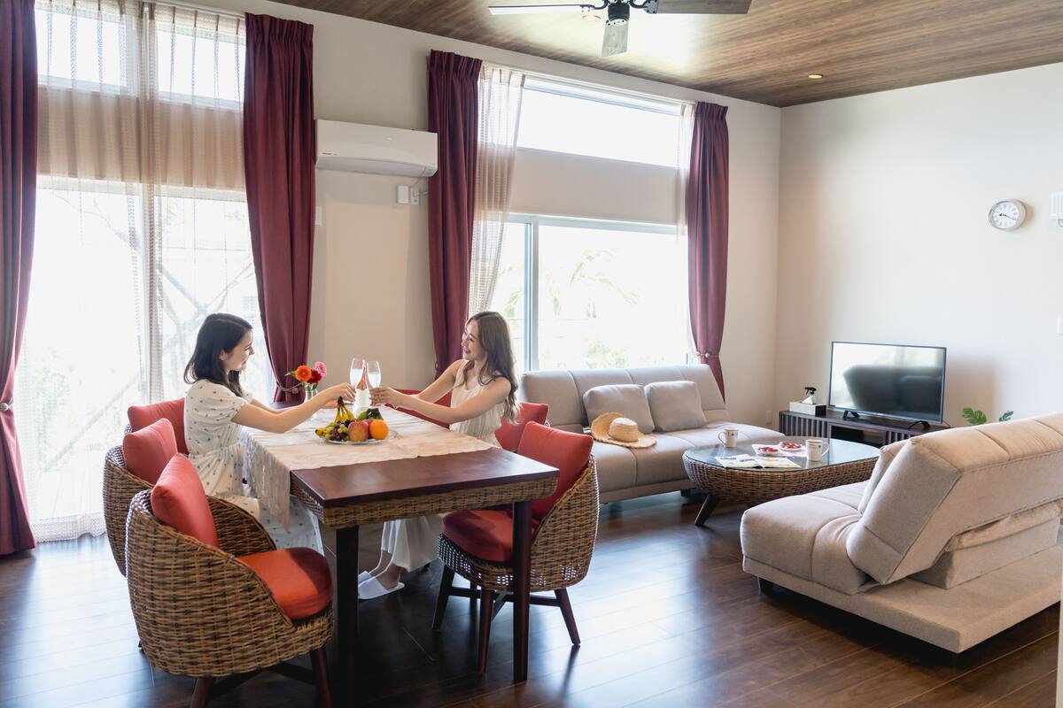 A modern living room with a dining table, wicker chairs, a sofa, and a television.