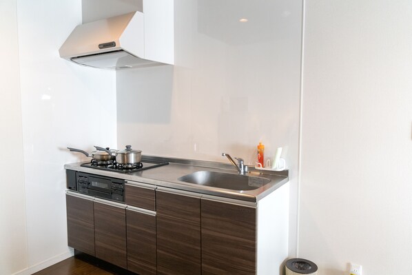 Una cocina moderna con estufa de acero inoxidable, lavamanos y armarios de madera.