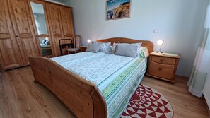 A bedroom with a wooden bed, a nightstand, a dresser, and a mirror.