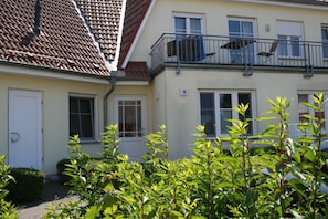 A two-story building with a balcony, a door, and windows.