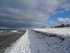 A snow-covered beach with a pier in the background.