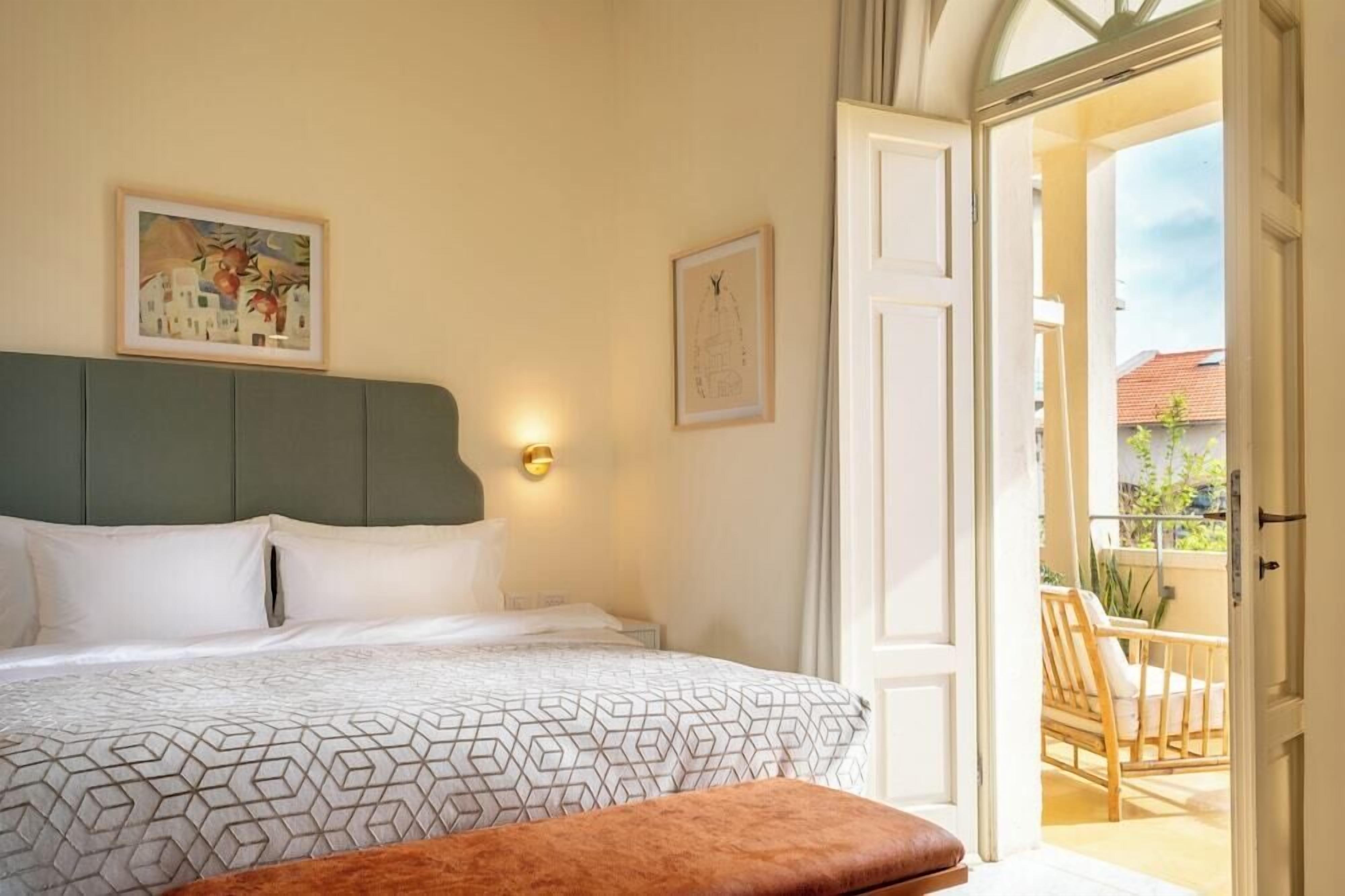 A bedroom with a bed, a headboard, a wall-mounted light, and a door leading to a balcony.