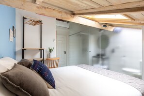 A bedroom with a bed, pillows, a small table with a plant, and a wardrobe. - Selina Neve Tzedek (Tel Aviv)