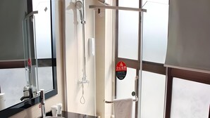 Une salle de bain moderne avec un grand miroir, un lavabo rond, une douche en verre et un porte-serviettes.