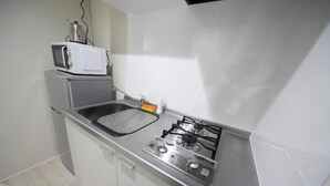 A compact kitchen with a microwave, sink, and gas stove.