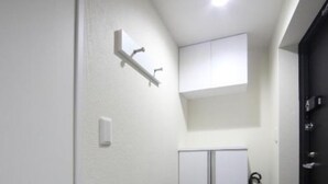 A narrow hallway with a white door on the left, a black door on the right, and a white wardrobe in the center.