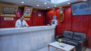 A reception area with a marble counter, a clock, and a framed portrait. - Al Karnak Hotel (Dubai)