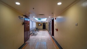 A hotel corridor with a sign indicating room numbers 414-419, a reception desk, and a waiting area with chairs. - Al Karnak Hotel (Dubai)