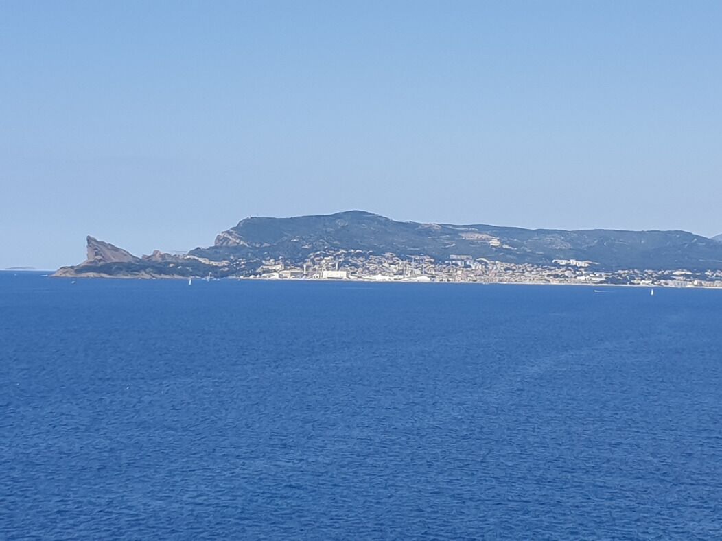 Un paysage urbain côtier, avec une colline bien visible et une étendue d’eau au premier plan.