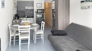 Un ambiente compatto con angolo cottura, zona pranzo e divano.