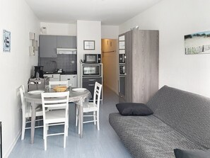 A compact living space with a kitchenette, dining area, and a sofa.