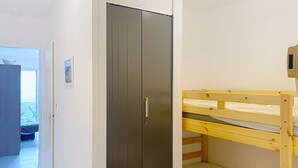 Una camera da letto con un letto a castello, un armadio e una porta che dà su un'altra stanza.