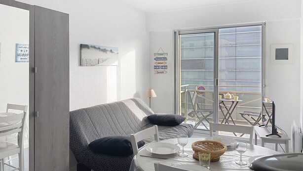 Una camera moderna con divano, tavolo da pranzo e un balcone con vista.