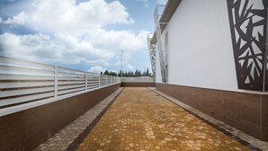 A covered walkway with a patterned floor, white railings, and a decorative wall panel.