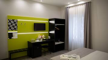 Een moderne hotelkamer met een bed, een bureau, een stoel, een televisie en een kledingkast.