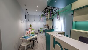 A modern kitchen with a central island, pendant lights, and hanging plants.