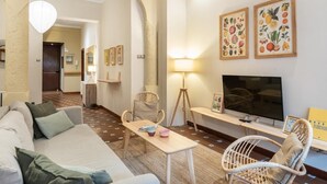 Un accogliente soggiorno con divano, poltrone, televisore e opere d'arte alle pareti.