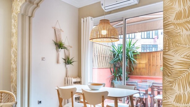 Zona pranzo con tavolo e sedie, un lampadario e vista sull'esterno.
