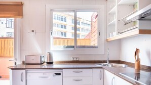Una cucina moderna con lavastoviglie integrata, una finestra vista edifici e un lavello in acciaio inossidabile.