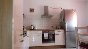 Una cucina con mobili bianchi, un forno in acciaio inossidabile, un tostapane e un frigorifero.