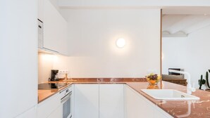 A modern kitchen with white cabinets, a marble countertop, a built-in oven, and a sink.