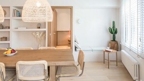 A dining area with a wooden table, wicker chairs, and woven pendant lights.