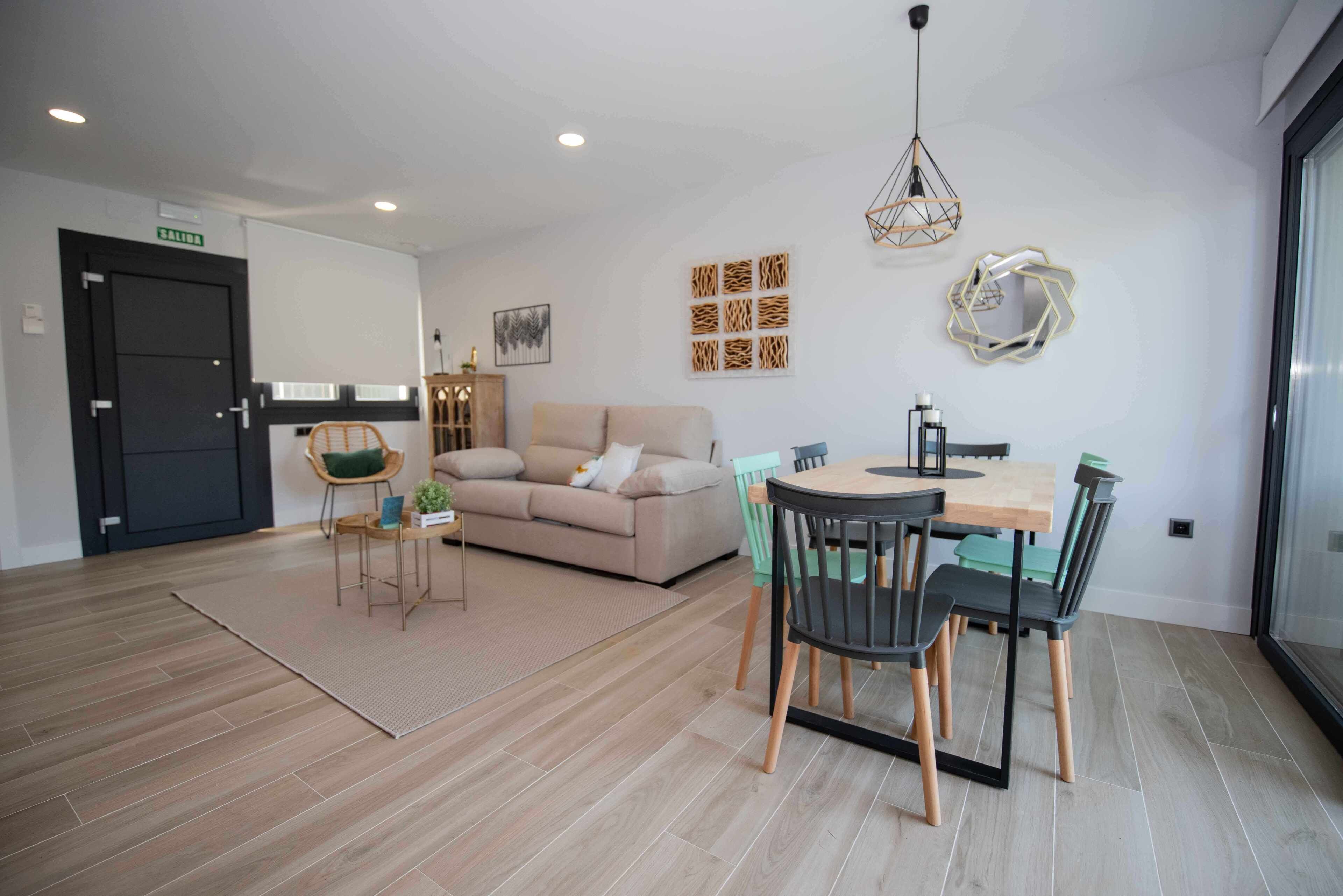 Un salon moderne avec un canapé, une table à manger et des chaises, un tapis et des œuvres d’art murales.