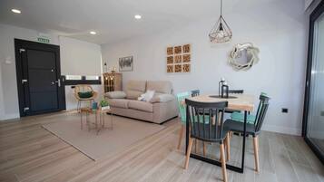 Un salon moderne avec un canapé, une table à manger et des chaises, un tapis et des œuvres d’art murales.
