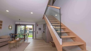 Ein modernes Wohnzimmer mit einer Holztreppe, einem Essbereich und Blick ins Freie.