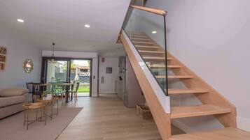 Un salon moderne avec un escalier en bois, un coin repas et une vue sur l’extérieur.