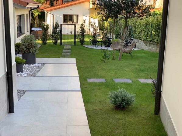 A modern house with a well-maintained lawn, a hammock, and a gated entrance.